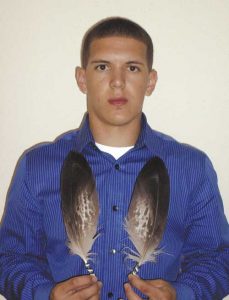 Photo of young man holding 2 eagle feathers