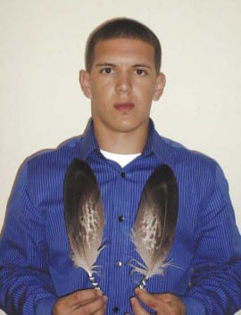 Photo of young man holding 2 eagle feathers