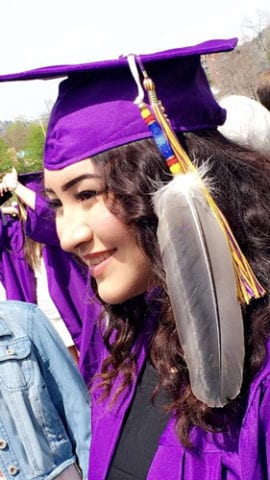 Photo of graduate in cap and gown with eagle feather