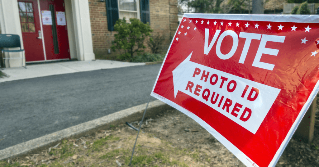 Photo of sign pointing to polling place with text, Photo ID required