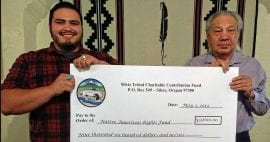 Photo of Gaylen Edmo and NARF Executive Director John Echohawk holding ceremonial check from Siletz Tribe