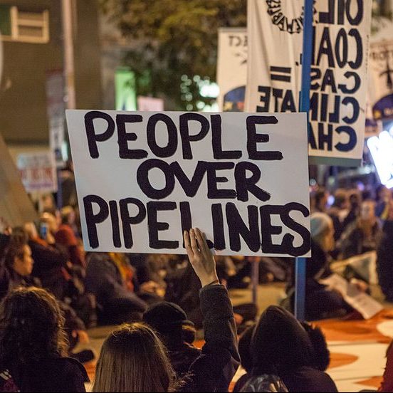 Protest sign: People Over Pipelines. Pax Ahimsa Gethen [CC BY-SA 4.0 (https://creativecommons.org/licenses/by-sa/4.0)]