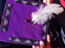 Photo of eagle feather attached to beaded graduation cap