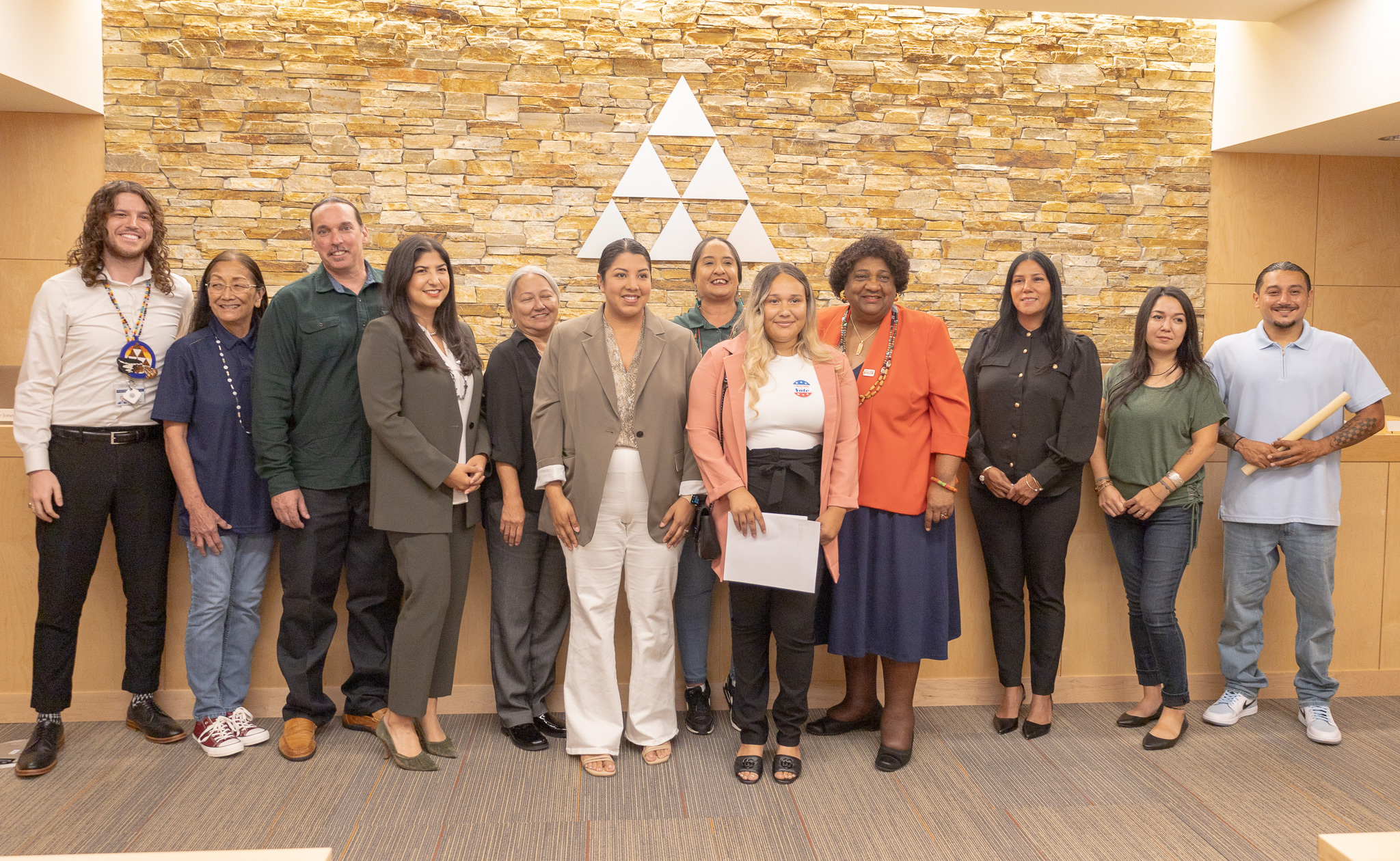 Members of tribal and state representatives standing infront of tribal council headquarters.