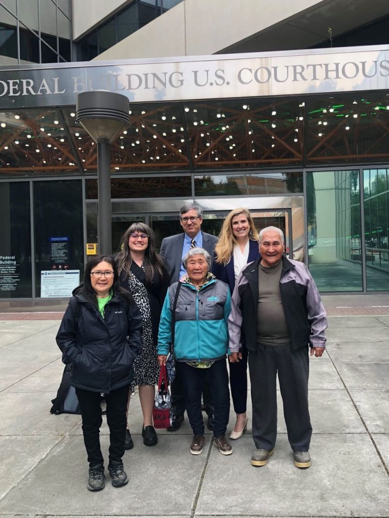 Group of six smiling people standing in front of courthouse. 