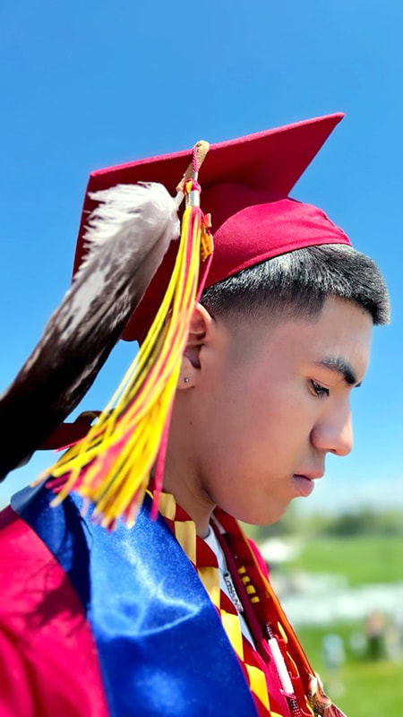 Graduating student with an eagle plume hanging from his mortarboard cap. 